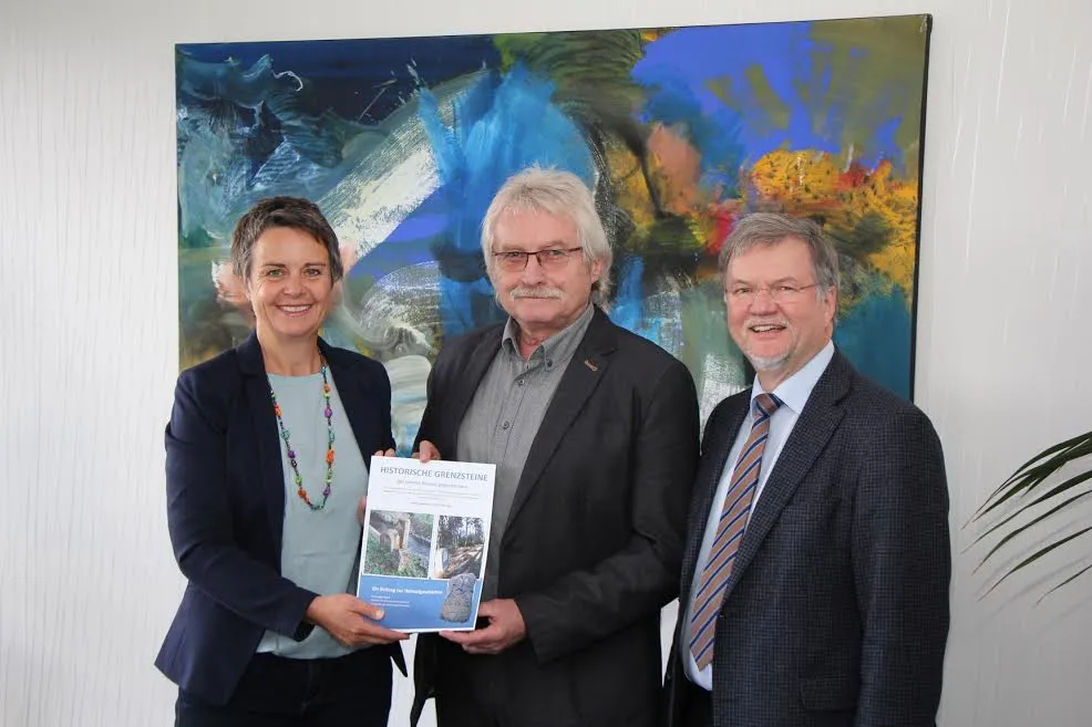 Jürgen Daum (Mitte) und Gerhard Lips (Amt für Bodenmanagement) präsentieren Landrätin Kirsten Fründt die neue, 216 Seiten starke Dokumentation über den historischen Grenzverlauf zwischen Hessen und Nassau. Foto: Landkreis Marburg-Biedenkopf